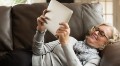 Senior woman reclining on sofa looking at digital tablet