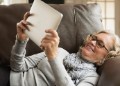 Senior woman reclining on sofa looking at digital tablet